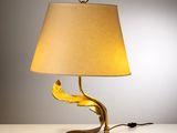 lampe de table en feuille d'or avec un abat-jour beige posée sur une table blanche