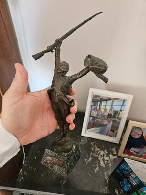 une personne tenant une statue en bronze représentant un homme tenant un marteau