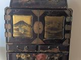 une petite commode posée sur une table à côté d'un livre