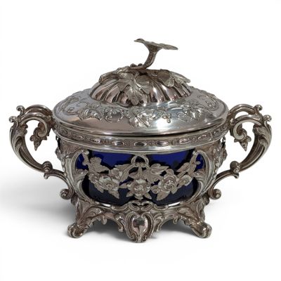 an antique silver and blue glass covered dish with a bird on top