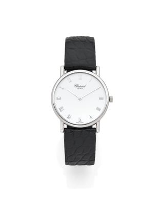 gros plan d'une montre sur une surface blanche avec un bracelet noir