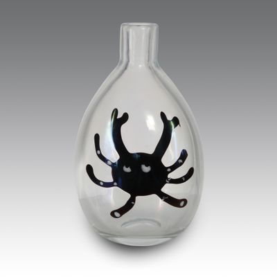 un vase en verre avec une araignée noire à l'intérieur