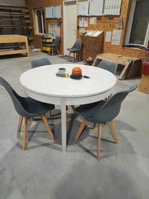 une table blanche entourée de quatre chaises dans une pièce