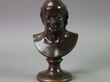 a bronze bust of a man on a pedestal with a gray background
