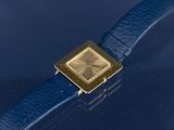 a gold watch on a blue leather strap on a blue surface