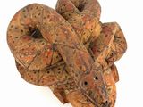 a wooden sculpture of a snake on a white surface