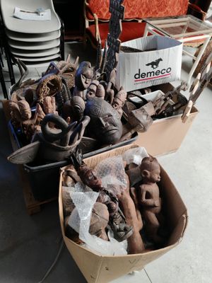 deux cartons contenant des sculptures en argile posés par terre, à côté d'un carton contenant d'autres objets