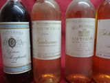 four bottles of wine are lined up in a row on a pink background