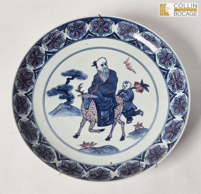une vieille assiette bleue et blanche représentant un homme chevauchant une chèvre