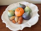 une assiette blanche posée sur une table, sur laquelle se trouvent des fruits et des noix