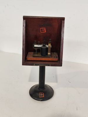 un microscope à l'ancienne, dans un coffret en bois posé sur un socle métallique