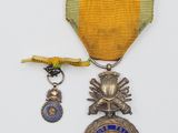 une image représentant une médaille entourée d'un ruban et une médaille sur laquelle est posée une autre médaille