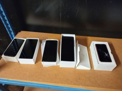 Quatre téléphones portables sont posés sur une table recouverte de boîtes.