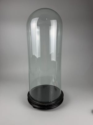 a glass clochet with a black base on a table