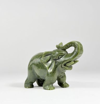 une statue d'éléphant verte posée sur une surface blanche