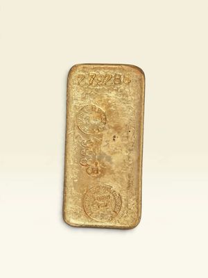 un lingot d'or posé sur une surface blanche, sur fond blanc
