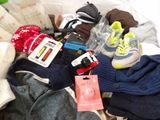 a basket full of clothes and shoes on a bed