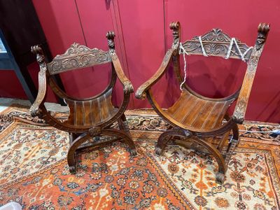 une paire de chaises anciennes en bois sculpté posées sur un tapis devant un mur rouge