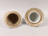 two vases sitting side by side on a white surface