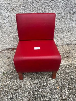 a red chair sitting on top of a cement floor next to a wall