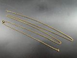 three gold chain necklaces on a black surface