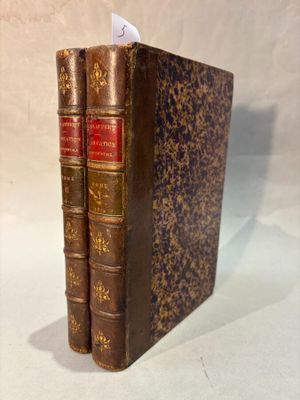 two old books are stacked on top of each other on a table