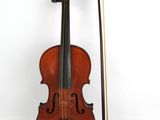 un vieux violon avec un archet et un repose-archet posé sur une surface blanche