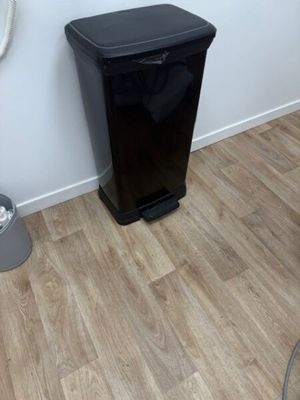 une poubelle noire posée à côté des toilettes dans une salle de bains
