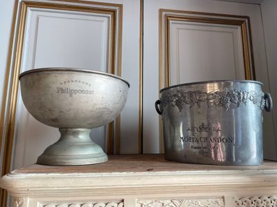 two silver pots sitting on top of a mantle