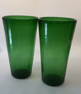 two green glass cups sitting on a white surface