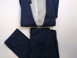 un costume bleu marine avec une chemise et un pantalon à rayures blanches, posé sur une table blanche