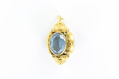 un gros plan d'un pendentif en pierre dorée et bleue sur fond blanc
