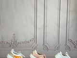 five pairs of white and pink sneakers lined up on a wooden table