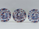 three blue and white plates with red and orange designs on them