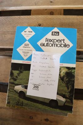 un livre posé sur un banc en bois, avec une voiture en arrière-plan