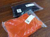 deux sacs contenant des vêtements orange et noirs, posés sur un plancher en bois