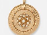 un gros plan d'un pendentif en or orné de perles sur fond blanc