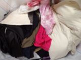 a pile of clothes that is sitting on a bed