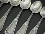 six cuillères en argent sont alignées sur une surface noire