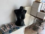 a black mannequin sitting on a bench in the corner of a room
