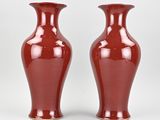 pair of red vases sitting on a white surface next to each other