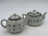 two white teapots with asian writing on them sitting on a table
