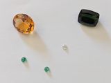 trois pierres précieuses de couleurs différentes sur un fond blanc, dont une verte et une marron