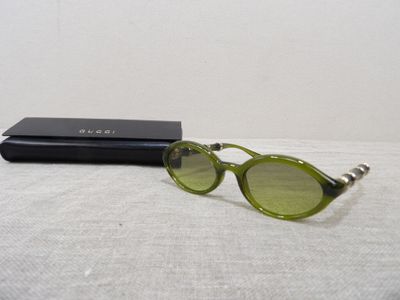 chanel sunglasses with green lenses and case on a white surface