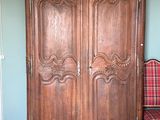 une armoire en bois dans une pièce où se trouve une chaise à carreaux
