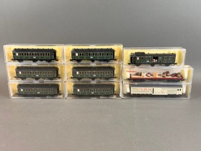 quatre trains miniatures sont alignés dans des boîtes en plastique posées sur une table