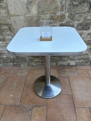 a white table with a glass on it on a brick floor