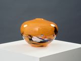 an orange vase sitting on top of a white pedestal