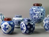 several blue and white vases with lids are lined up on a table