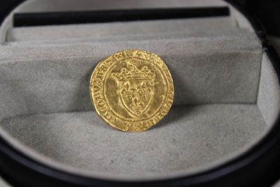 une image représentant une pièce d'or posée dans une boîte sur une table